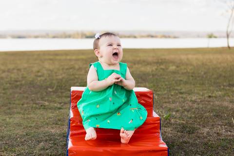 Detalhes sensíveis e pureza da infância ao ar livre. Cecília descalça no gramado brincando e sorrindo em um dia de sol e lazer em família.'