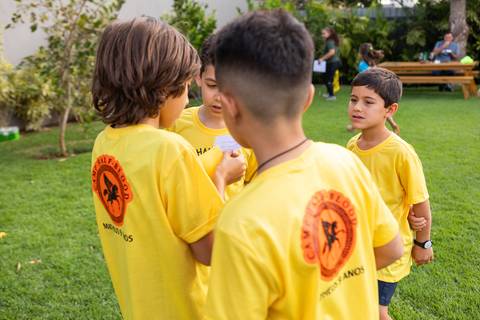 Crianças caracterizadas com camisetas de chalés mitológicos em festa infantil. Registro do desenvolvimento saudável e interação dos amigos no aniversário do Matheus.'