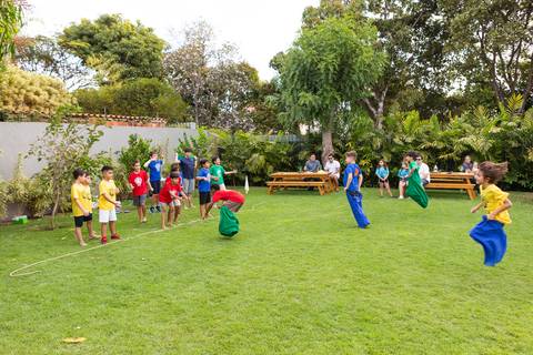 Brincadeiras e gincanas ao ar livre em aniversário infantil. Registro dinâmico de corrida de saco e atividades recreativas focadas no bem-estar e na diversão em Brasília.'