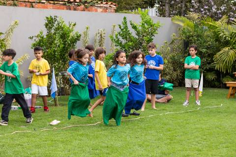 Brincadeiras e gincanas ao ar livre em aniversário infantil. Registro dinâmico de corrida de saco e atividades recreativas focadas no bem-estar e na diversão em Brasília.'