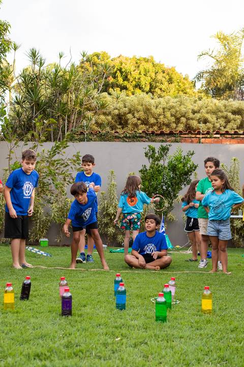 Brincadeiras e gincanas ao ar livre em aniversário infantil. Registro dinâmico de corrida de saco e atividades recreativas focadas no bem-estar e na diversão em Brasília.'