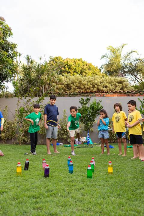 Brincadeiras e gincanas ao ar livre em aniversário infantil. Registro dinâmico de corrida de saco e atividades recreativas focadas no bem-estar e na diversão em Brasília.'