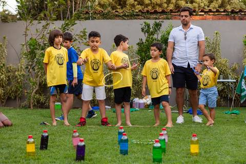 Brincadeiras e gincanas ao ar livre em aniversário infantil. Registro dinâmico de corrida de saco e atividades recreativas focadas no bem-estar e na diversão em Brasília.'