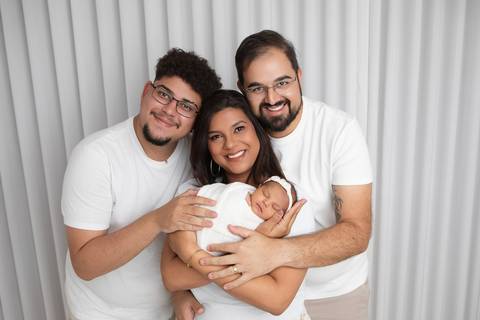 União e harmonia familiar na chegada da Ísis. O irmão mais velho e os pais reunidos para celebrar a nova vida com roupas brancas coordenadas.'