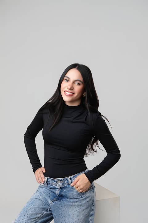 Retrato individual feminino em Brasília. Letícia em pose casual e moderna com blusa preta de gola alta e calça jeans.'