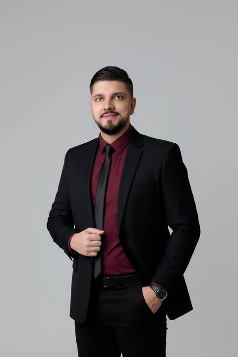 Posicionamento de imagem para consultores e mentores. Foto de estúdio masculina com traje social fino e fundo cinza-claro.'