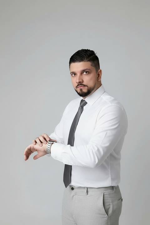 Retrato corporativo dinâmico masculino. Foto profissional simulando gestão de tempo e planejamento com camisa social e gravata.'
