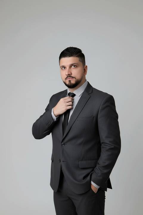 Retrato de liderança e autoridade corporativa. Vitor em pose clássica ajustando o traje social em ensaio de estúdio.'