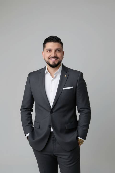 Foto corporativa de posicionamento de imagem. Vitor vestindo terno chumbo e sorrindo para retrato de perfil profissional e LinkedIn.'