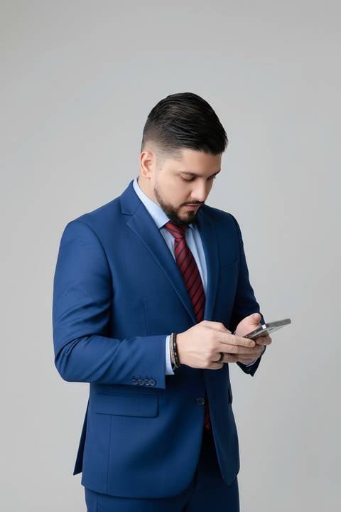 Fotografia profissional dinâmica para redes sociais. Consultor interagindo com smartphone em retrato moderno com terno azul.'