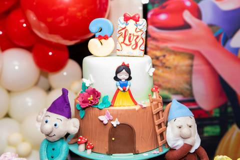 Detalhes da decoração infantil de 3 anos inspirada no tema Branca de Neve. Registro lúdico com doces personalizados, bolo temático e elementos do bosque em Brasília.'