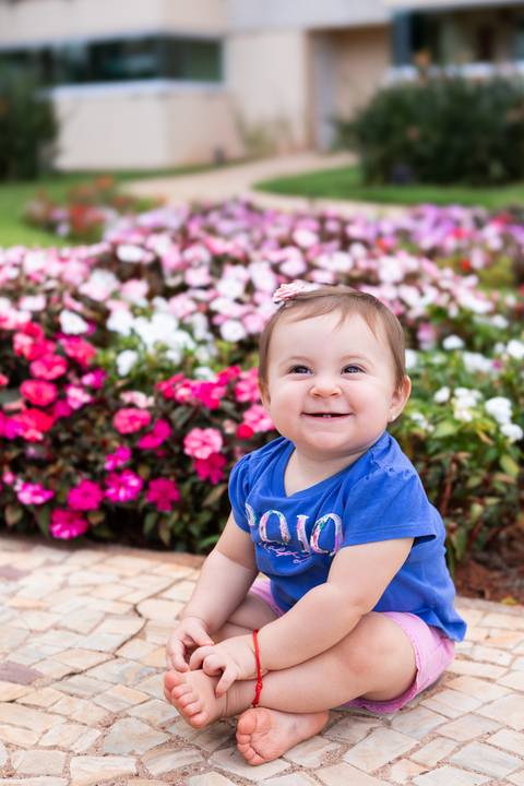 Contato com a natureza e sensibilidade na infância. A pequena Cecília interagindo com o ambiente florido do jardim.'