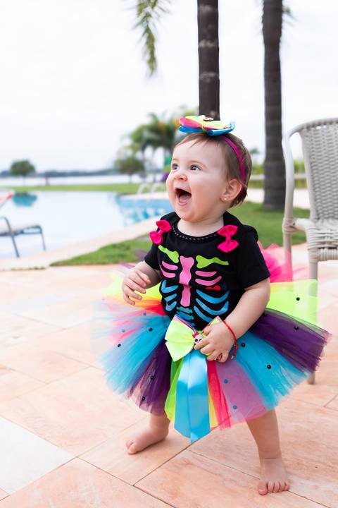 Celebração e alegria em família ao ar livre. Cecília com fantasia de tutu colorida aproveitando o dia na área de lazer.'