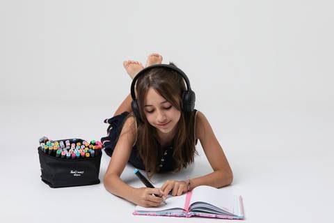 Atividades criativas, música e a essência da juventude. Meninas interagindo com fone de ouvido, canetas coloridas e elementos lúdicos no estúdio.'