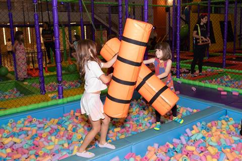 Aventura, movimento e pura diversão na infância. Crianças se divertindo na tirolesa e na piscina de bolinhas durante comemoração de aniversário.'
