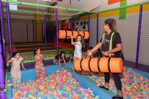 Aventura, movimento e pura diversão na infância. Crianças se divertindo na tirolesa e na piscina de bolinhas durante comemoração de aniversário.'
