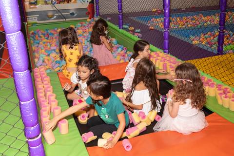 Aventura, movimento e pura diversão na infância. Crianças se divertindo na tirolesa e na piscina de bolinhas durante comemoração de aniversário.'