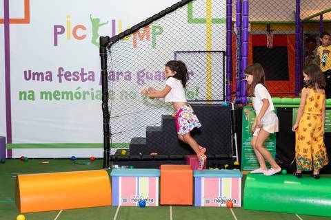 Aventura, movimento e pura diversão na infância. Crianças se divertindo na tirolesa e na piscina de bolinhas durante comemoração de aniversário.'