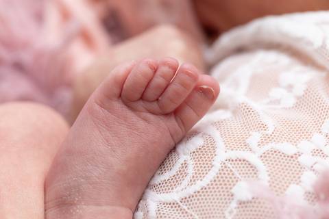 Detalhes sensíveis e puros do recém-nascido. Expressões serenas, pezinhos, orelhinha e mãozinhas da pequena Laura em registro focado no bem-estar infantil.'