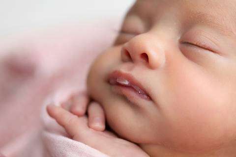 Detalhes sensíveis e puros do recém-nascido. Expressões serenas, pezinhos, orelhinha e mãozinhas da pequena Laura em registro focado no bem-estar infantil.'