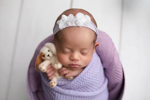 A pureza e o aconchego do sono do bebê. Laura abraçada a um mini urso de pelúcia em cenário clássico e minimalista claro no Distrito Federal.'