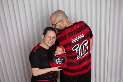 A alegria e as paixões familiares compartilhadas desde o berço. A recém-nascida Laura envolta em wrap temático do Flamengo em estúdio minimalista.'