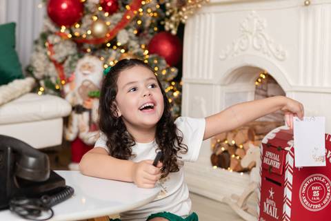 Imaginação e momentos lúdicos no desenvolvimento infantil. A pequena Alana interagindo com cenário tradicional natalino em Brasília.'