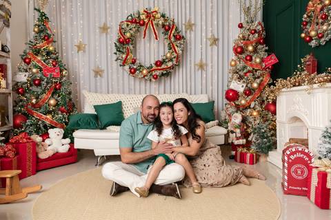 Retrato de família em cenário acolhedor e iluminado. Kelen, Thiago e Alana reunidos no Distrito Federal para celebrar as tradições familiares.'