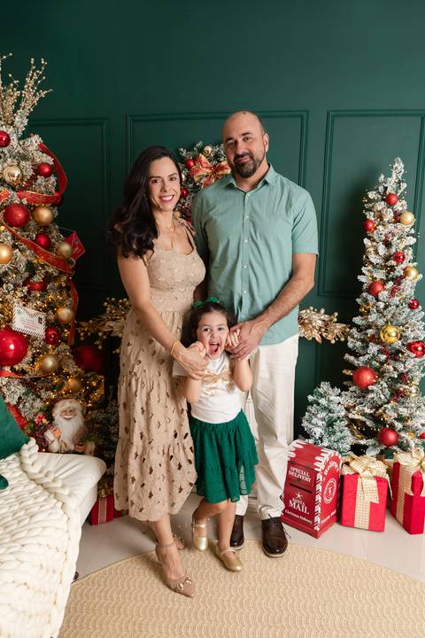 Aconchego e união familiar em Brasília - DF. Pais e filha vestindo figurinos coordenados em harmonia com os tons clássicos do cenário.'