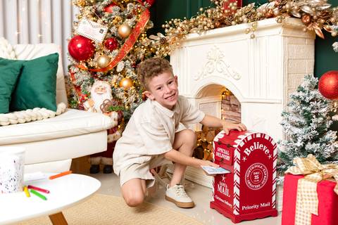 Momentos lúdicos e imaginação no crescimento infantil. Miguel interagindo com cenário tradicional de fim de ano em estúdio minimalista.'
