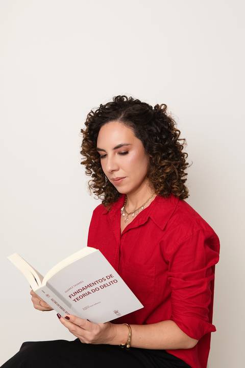 Foto profissional de posicionamento de imagem jurídica. Professora de direito Michelle Tonon concentrada na leitura de livro técnico para cursinho preparatório.'