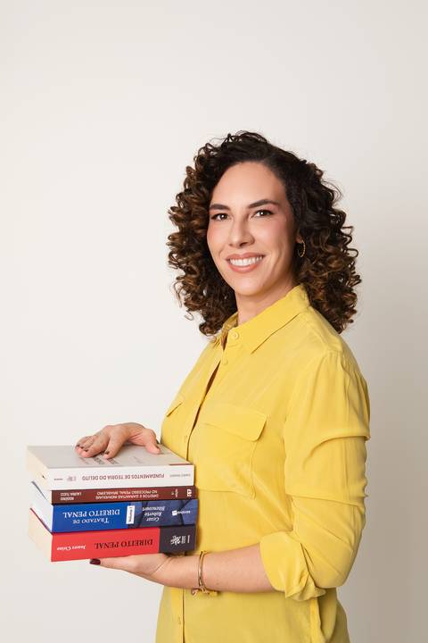 Retrato de estúdio para mentores e professores de direito. Michelle Tonon sorrindo com livros de estudo em ensaio focado em dinamismo e educação.'