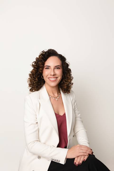 Retrato de autoridade profissional feminina em Brasília. Defensora criminal Michelle Tonon vestindo blazer branco em imagem clássica e acolhedora para redes sociais.'