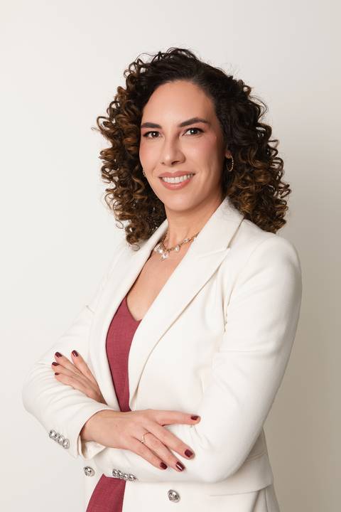Posicionamento de imagem estratégica para carreiras jurídicas. Michelle Tonon em pose de liderança e segurança com terno feminino claro em estúdio.'