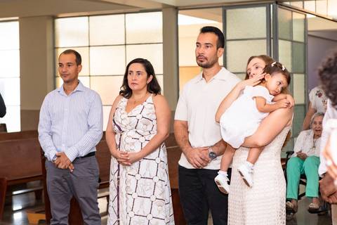 Momentos de fé e espiritualidade na infância. Registro do rito de batismo da Aurora com a presença dos padrinhos e familiares na igreja.'