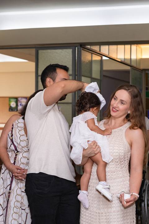 Momentos de fé e espiritualidade na infância. Registro do rito de batismo da Aurora com a presença dos padrinhos e familiares na igreja.'