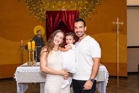 União e harmonia familiar em Brasília. A mamãe Karen, familiares e convidados reunidos no altar para celebrar o batizado da Aurora.'