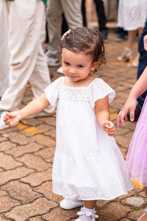 Desenvolvimento saudável e pura espontaneidade infantil. Aurora se divertindo ao ar livre com os pais após a cerimônia de batizado.'