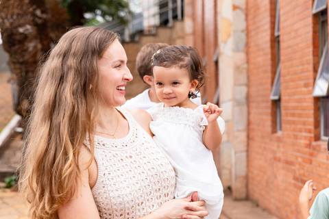Desenvolvimento saudável e pura espontaneidade infantil. Aurora se divertindo ao ar livre com os pais após a cerimônia de batizado.'