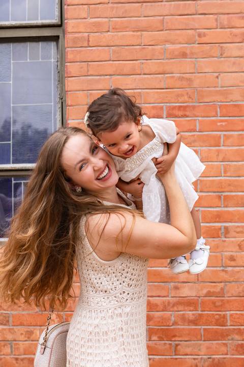 Desenvolvimento saudável e pura espontaneidade infantil. Aurora se divertindo ao ar livre com os pais após a cerimônia de batizado.'