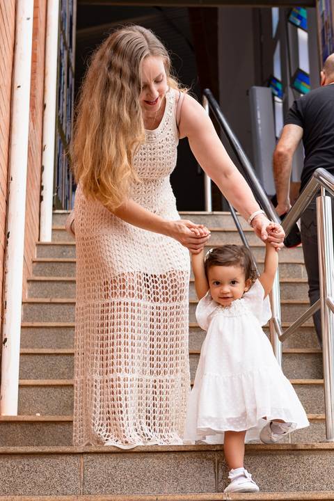 Desenvolvimento saudável e pura espontaneidade infantil. Aurora se divertindo ao ar livre com os pais após a cerimônia de batizado.'