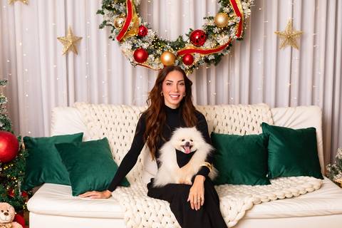 Retrato afetivo em estúdio. Taty posando com seu cachorro de estimação em cenário festivo de fim de ano.'