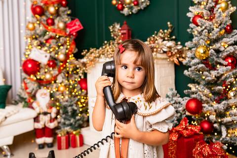 Brincadeiras lúdicas e imaginação no crescimento infantil. Liz interagindo com telefone antigo de forma divertida no estúdio.'