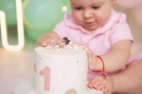 Estímulos lúdicos e comemoração saudável na infância. Detalhe do bebê se divertindo com o bolo de aniversário.'