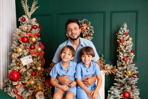 Conexão paterna e laços de amor em família. O pai Ariel cercado pelo carinho de Mateus e Rafael vestindo roupas azuis coordenadas.'