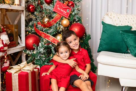 A cumplicidade e o carinho entre irmãos na infância. Os irmãos João e Isabela em momento descontraído e alegre de fim de ano.'