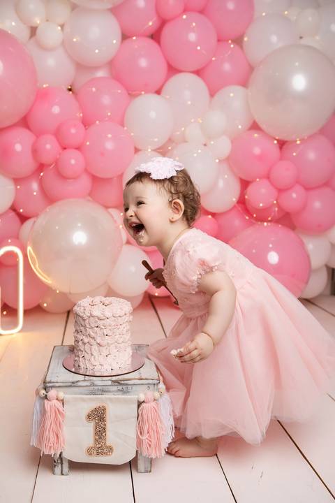Desenvolvimento infantil e curiosidade do bebê. Maria Helena interagindo com seu bolo de aniversário de um ano.'