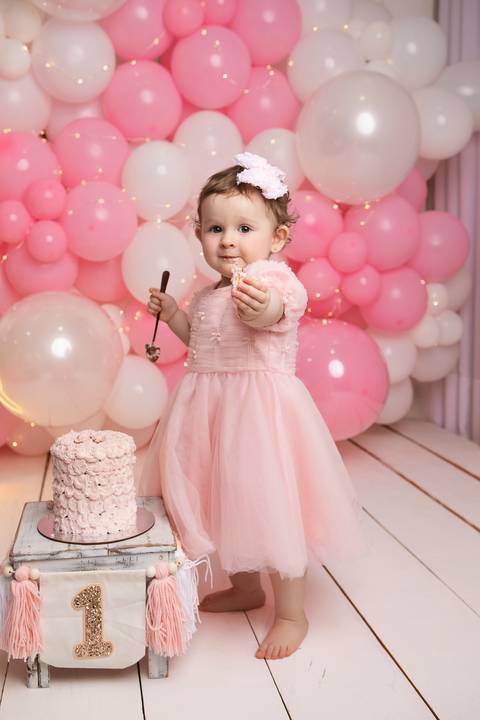 Espontaneidade e diversão no Smash the Cake no DF. Detalhe de bebê se divertindo em ensaio de aniversário.'