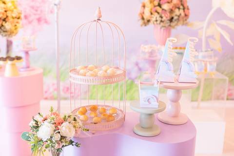 Doces decorativos em festa de aniversário infantil. Torre temática em tons de rosa e lilás para comemoração de um ano.'