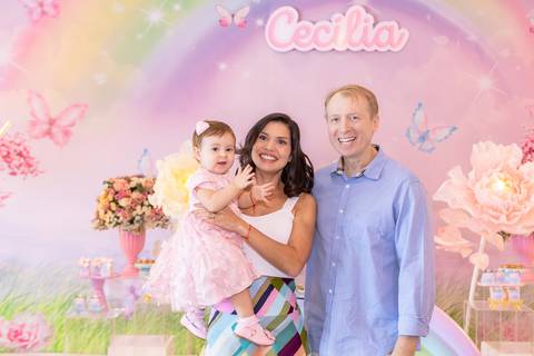 Retrato de família em aniversário de um ano em Brasília. Mariana e Vincenzo com a filha Cecília de vestido rosa.'